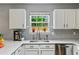 Bright kitchen with white cabinets, stainless steel sink, and a view of the backyard through the window at 408 Sam Cobb Ct, Woodstock, GA 30188