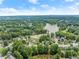 Aerial view showcasing a community with a serene lake, mature trees, and manicured lawns at 1647 Tunbridge Ln, Lawrenceville, GA 30043