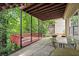 Back patio with a wood deck and a covered area is surrounded by lush greenery and an outdoor table set at 1647 Tunbridge Ln, Lawrenceville, GA 30043