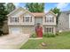 Charming split-level home featuring a manicured lawn, red shutters, and a two-car garage at 1647 Tunbridge Ln, Lawrenceville, GA 30043
