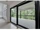 View of wooden back porch, railing, and wooded backyard through sliding glass doors and windows at 165 Westbrook St, Buford, GA 30518