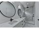 Bathroom vanity and shower with white marble tiling and black fixtures and dual round mirrors at 165 Westbrook St, Buford, GA 30518