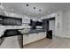Open concept kitchen with black and white cabinets, marble countertops, and a central island with pendant lights at 165 Westbrook St, Buford, GA 30518