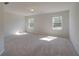 Bright bedroom with plush carpeting and natural light from two large windows at 228 Chiswick Loop, Stockbridge, GA 30281