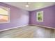 A bedroom with wood flooring, two windows, a ceiling fan, and light purple walls at 286 Booker Sw St, Atlanta, GA 30315