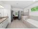 Light-filled bathroom with dual vanity, granite counters, soaking tub, and frameless glass shower at 4910 Conover Dr, Atlanta, GA 30338