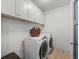 Functional laundry room with white cabinets, modern washer and dryer, and wood-look flooring at 4910 Conover Dr, Atlanta, GA 30338