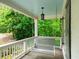 Cozy covered porch with light blue ceiling, hanging porch swing, and views of mature trees at 4910 Conover Dr, Atlanta, GA 30338