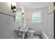 Bright bathroom features a pedestal sink, classic black and white tile floor, and window view at 6104 Floyd St, Covington, GA 30014