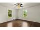 Bright bedroom with hardwood floors, ceiling fan, and natural light streaming through the windows at 6104 Floyd St, Covington, GA 30014