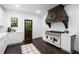 Bright kitchen features white cabinets, stainless steel range with custom wood vent hood and hardwood floors at 6104 Floyd St, Covington, GA 30014