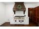 Gourmet kitchen boasts a premium range with custom wood vent hood and elegant white cabinetry at 6104 Floyd St, Covington, GA 30014