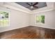 Spacious primary bedroom featuring hardwood floors, tray ceiling, and natural light from two large windows at 704 Willowwind Dr, Loganville, GA 30052