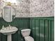 Stylish half bathroom featuring floral wallpaper, a pedestal sink, and unique green wainscoting at 704 Willowwind Dr, Loganville, GA 30052