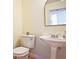 Cozy bathroom with white pedestal sink, matching toilet, and arched mirror at 12955 Mariners Ct, Alpharetta, GA 30005