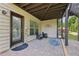 Covered patio with stone pavers, seating area, door to basement and lush greenery at 4630 Carriage Walk Ln, Cumming, GA 30040
