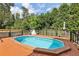 Backyard in-ground pool with wooden decking, surrounded by mature trees for privacy at 4630 Carriage Walk Ln, Cumming, GA 30040