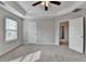 Bright bedroom featuring neutral carpeting, tray ceiling with fan, and two windows offering ample natural light at 1345 Aster Ives Dr, Lawrenceville, GA 30045