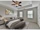 Stylishly staged primary bedroom featuring a tray ceiling, ceiling fan, and a comfortable king bed at 1345 Aster Ives Dr, Lawrenceville, GA 30045