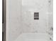 Beautifully tiled bathroom with tub and shower featuring white marble-look tile and a built-in niche at 213 Yuba Walk, Lawrenceville, GA 30046