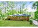 Rear view of a brick house showcasing a large, grassy backyard surrounded by mature trees at 3697 Wisteria Sw Ln, Atlanta, GA 30331