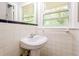 Cozy bathroom featuring a white pedestal sink, tiled walls, and a window for natural light at 3697 Wisteria Sw Ln, Atlanta, GA 30331