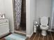 Well-lit bathroom features a white toilet and vanity, with a shower featuring brown tile and patterned curtain at 5655 Lake Forrest Dr, Atlanta, GA 30342