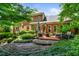 Beautiful backyard with a stone patio, outdoor dining, fire pit, lush landscaping, and home exterior at 1676 Grove Park Way, Decatur, GA 30033