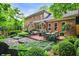 The brick patio features an outdoor dining area, fire pit, lounge chairs, lush landscaping, and home exterior at 1676 Grove Park Way, Decatur, GA 30033