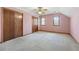 Carpeted bedroom featuring three wood-paneled closets, a fan, and two sunny, windowed walls at 195 Willow Way, Stockbridge, GA 30281