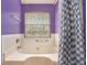 Bright bathroom with a window over the tub and a blue and white checkered shower curtain at 3740 Arminto Dr, Ellenwood, GA 30294