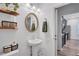 Stylish half bath with pedestal sink, oval mirror, and decorative floating shelves at 4658 Electric Sw Ave, Mableton, GA 30126