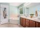 This main bathroom features dual sinks, wooden cabinets, a soaking tub, and plenty of natural light at 6155 Falls Landing Dr, Cumming, GA 30040
