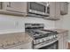 Close-up of stainless steel gas range with granite countertops and white subway tile backsplash at 1610 Habersham Villa Dr, Cumming, GA 30041