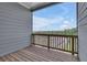 Covered patio with wood flooring and wooden railing, showcasing a view of the surrounding greenery at 1610 Habersham Villa Dr, Cumming, GA 30041