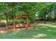 Backyard featuring a wooden swing, lush green grass, mature trees, and landscaping at 1775 Potomac Ct, Lawrenceville, GA 30043