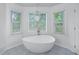 Bright bathroom featuring a modern freestanding tub with natural light from large windows at 1775 Potomac Ct, Lawrenceville, GA 30043