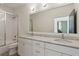 Bathroom with double vanity, white cabinets, marble countertop, and tiled shower at 6925 Colfax Ave, Cumming, GA 30040
