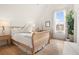 Bright bedroom features light wood flooring, a large window, and a sleigh bed at 11190 Serenbe Ln, Chattahoochee Hills, GA 30268