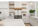 Modern kitchen with white cabinets, open shelves, and stainless steel appliances for a clean design at 11190 Serenbe Ln, Chattahoochee Hills, GA 30268