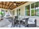 Covered outdoor seating area with a hanging chair, a dining table, and ceiling fans at 11190 Serenbe Ln, Chattahoochee Hills, GA 30268