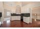 A kitchen features white cabinets and black countertops, with wood flooring and open access to other rooms at 5975 Tate Dr, Austell, GA 30106