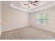 A main bedroom with neutral carpet, a tray ceiling, and a window provides a calm and serene space at 5975 Tate Dr, Austell, GA 30106