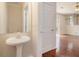 A powder room features a pedestal sink and hardwood flooring, conveniently located near the main living area at 5975 Tate Dr, Austell, GA 30106