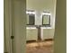 Bright bathroom featuring double sinks with stylish mirrors and travertine tile flooring at 6848 Timberhead Way, Lithonia, GA 30058