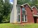 Angle of the brick house featuring large windows, partial siding and luscious green lawn at 6848 Timberhead Way, Lithonia, GA 30058