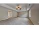 Large main bedroom with tray ceiling, ceiling fan, neutral carpet, and en suite access at 8256 Milam Loop, Fairburn, GA 30213