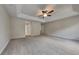 Spacious carpeted main bedroom showcasing tray ceiling, fan, and access to bathroom at 8256 Milam Loop, Fairburn, GA 30213
