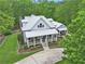 An aerial view shows a home with metal roof, inviting front porch, and well-maintained landscaping at 8901 Watkins Mill Rd, Winston, GA 30187