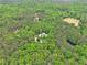 Distant aerial view of a house surrounded by dense, mature trees and a clear blue sky at 8901 Watkins Mill Rd, Winston, GA 30187